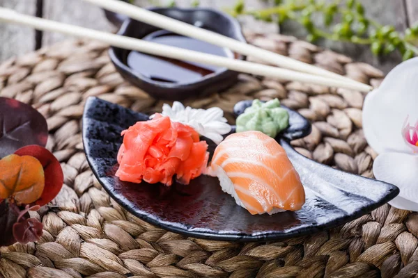 Set de sushi nigiri y rollos de sushi decorados con flores sobre fondo de bambú. Cocina japonesa. Enfoque selectivo — Foto de Stock
