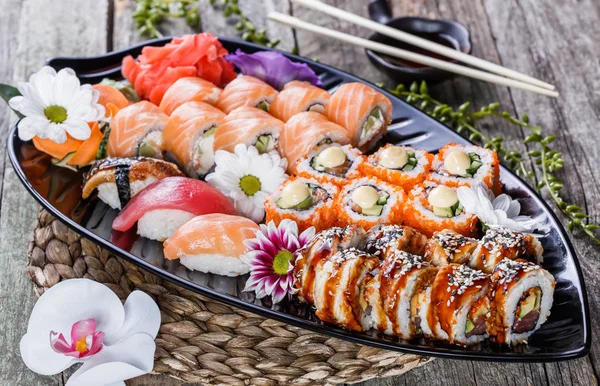 Set de sushi nigiri y rollos de sushi decorados con flores sobre fondo de bambú. Cocina japonesa. Enfoque selectivo — Foto de Stock