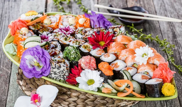 Set de sushi nigiri y rollos de sushi decorados con flores sobre fondo de bambú. Cocina japonesa. Enfoque selectivo — Foto de Stock