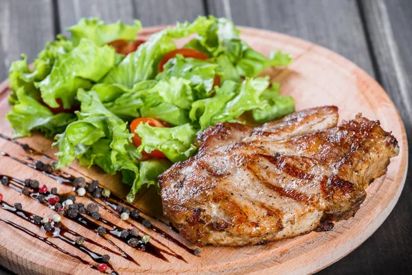 Grilled chicken meat with fresh vegetable salad, tomatoes and sauce on wooden cutting board — Stock Photo, Image