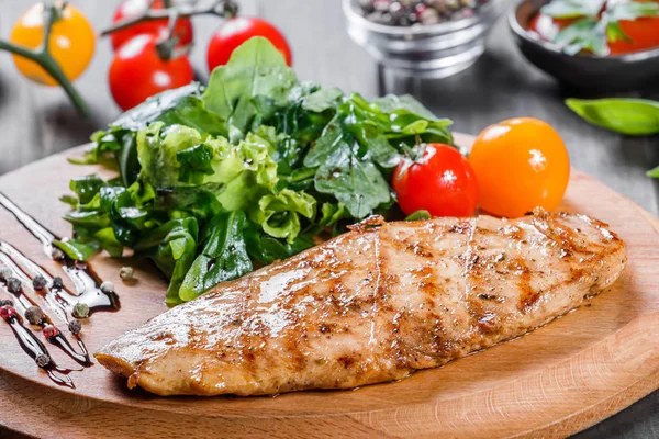 Gegrilltes Hühnerfilet mit frischem Gemüsesalat, Tomaten und Sauce auf Holzschneidebrett — Stockfoto