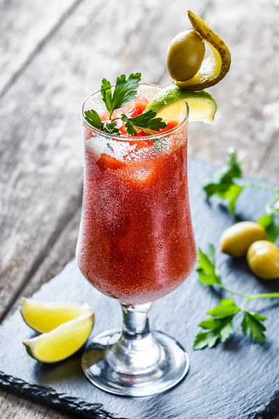 Bloody Mary cocktails with tomato juice and spicy vodka, decorated with pickle and olive garnish on stone slate background on rustic table. Summer drinks and alcoholic cocktails. — Stock Photo, Image