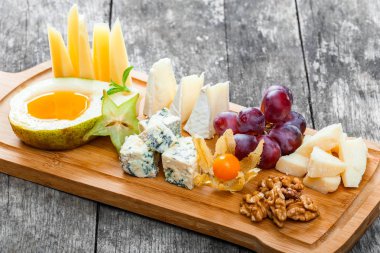 Peynir tabağı süslenmiş armut, tatlım, ceviz, üzüm, carambola, physalis ahşap arka plan üzerinde kesme tahtası üzerinde. Aperatifler ve şarap meze ayarlayın. Üstten Görünüm