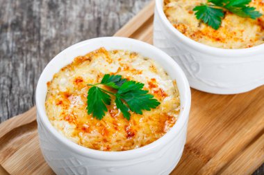 Sulu tavuk, mantar, krema sos ve peynir kesme tahtası ahşap arka plan üzerinde üzerinde sıcak Julienne iki kâse. Etli meze