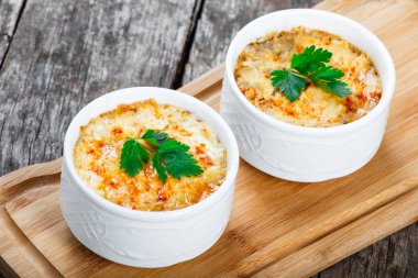 Sulu tavuk, mantar, krema sos ve peynir kesme tahtası ahşap arka plan üzerinde üzerinde sıcak Julienne iki kâse. Etli meze