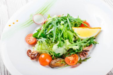 Deniz ürünleri salatası midye, mürekkep, ahtapot, roka, marul ve domates ahşap zemin üzerine kapatın. Akdeniz yemekleri