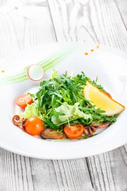 Deniz ürünleri salatası midye, mürekkep, ahtapot, roka, marul ve domates ahşap zemin üzerine kapatın. Akdeniz yemekleri