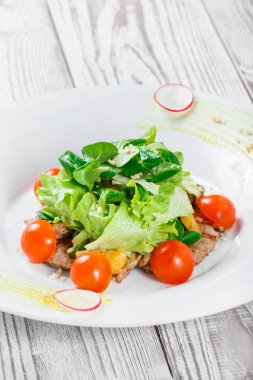 Taze salata tavuk göğsü, Bebek ıspanak, marul, domates ve peynirle ahşap arka plan üzerinde kapat