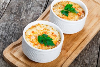 Sulu tavuk, mantar, krema sos ve peynir kesme tahtası ahşap arka plan üzerinde üzerinde sıcak Julienne iki kâse. Etli meze