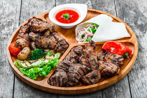 Surtido de deliciosa carne a la parrilla y verduras con ensalada fresca y salsa barbacoa en la tabla de cortar sobre fondo de madera de cerca. Platos de carne caliente. Vista superior — Foto de Stock