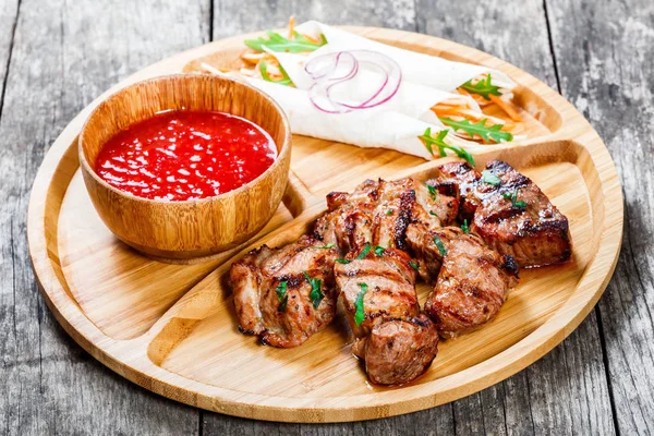 Izgara domuz eti ve sebze taze salata ve kesme tahtası üzerinde ahşap arka plan barbekü sosu ile kapatın. Sıcak et yemekleri. Üstten Görünüm