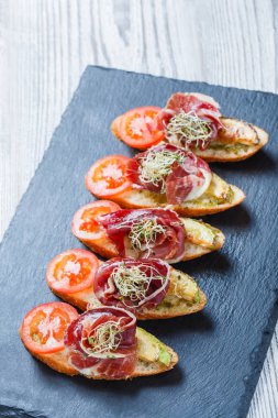 Meze bruschetta salam, domates, kabak ciabatta ekmeği taş arduvaz arka plan üzerinde tarih ile kapatın. Lezzetli aperatifler, sandviçler, crostini, parti ya da piknik zamanında antipasti. Üstten Görünüm