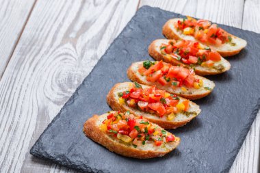 Meze bruschetta ciabatta ekmeği kayrak taş zemin üzerine doğranmış sebze ile kapatın. Lezzetli aperatifler, sandviçler, crostini, kanepe, parti ya da piknik zamanında antipasti. Üstten Görünüm