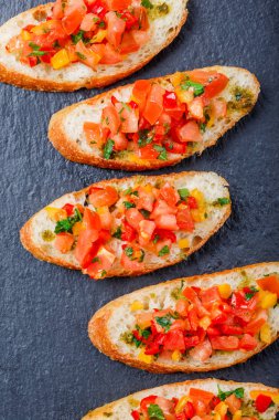 Meze bruschetta ciabatta ekmeği kayrak taş zemin üzerine doğranmış sebze ile kapatın. Lezzetli aperatifler, sandviçler, crostini, kanepe, parti ya da piknik zamanında antipasti. Üstten Görünüm