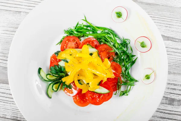 Salada fresca com tomates de cereja, pepino, rabanete, pimentão doce e cebola em uma chapa no fundo de madeira fecham. Vista superior — Fotografia de Stock