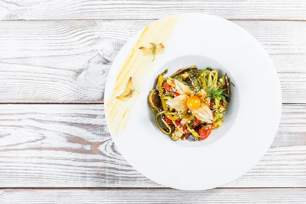 Salata tavuk göğsü ve ızgara sebzeler, patlıcan, tatlı biber, domates, avokado ve ahşap arka plan üzerinde plaka üzerinde physalis kapatın. Üstten Görünüm