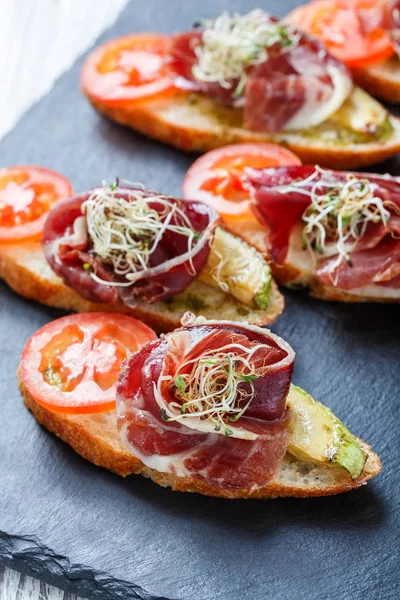 Meze bruschetta salam, domates, kabak ciabatta ekmeği taş arduvaz arka plan üzerinde tarih ile kapatın. Lezzetli aperatifler, sandviçler, crostini, parti ya da piknik zamanında antipasti. Üstten Görünüm