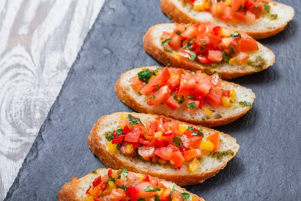 Meze bruschetta ciabatta ekmeği kayrak taş zemin üzerine doğranmış sebze ile kapatın. Lezzetli aperatifler, sandviçler, crostini, kanepe, parti ya da piknik zamanında antipasti. Üstten Görünüm