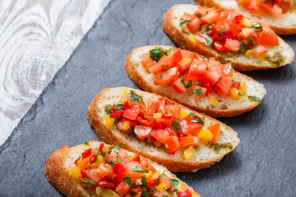 Meze bruschetta ciabatta ekmeği kayrak taş zemin üzerine doğranmış sebze ile kapatın. Lezzetli aperatifler, sandviçler, crostini, kanepe, parti ya da piknik zamanında antipasti. Üstten Görünüm