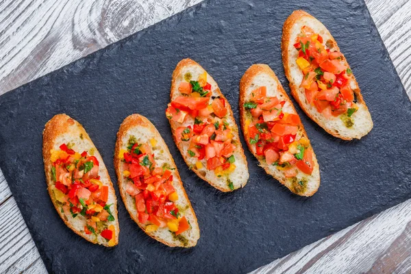 Meze bruschetta ciabatta ekmeği kayrak taş zemin üzerine doğranmış sebze ile kapatın. Lezzetli aperatifler, sandviçler, crostini, kanepe, parti ya da piknik zamanında antipasti. Üstten Görünüm