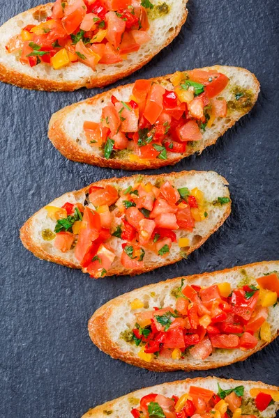 Meze bruschetta ciabatta ekmeği kayrak taş zemin üzerine doğranmış sebze ile kapatın. Lezzetli aperatifler, sandviçler, crostini, kanepe, parti ya da piknik zamanında antipasti. Üstten Görünüm