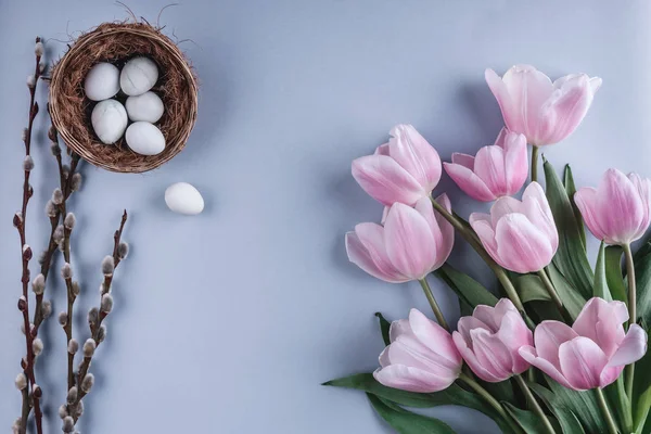 Ovos de Páscoa em ninho e flores de tulipa no fundo da primavera. Vista superior com espaço de cópia. Feliz cartão de Páscoa . — Fotografia de Stock