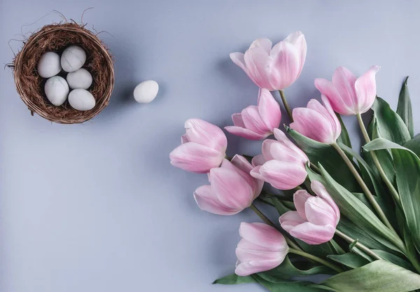 Ovos de Páscoa em ninho e flores de tulipas no fundo de primavera. Vista superior com espaço de cópia. Feliz cartão de Páscoa — Fotografia de Stock