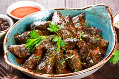 Doldurulmuş üzüm pirinç ve otlar ile plaka üzerinde ahşap arka plan - Dolma, tolma, sarma yaprak. Sağlıklı vegan gıda.