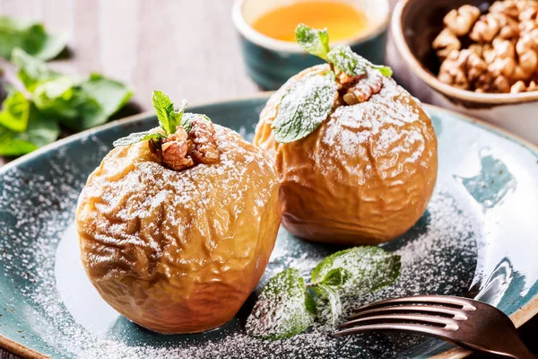 Manzanas al horno con canela, nueces y miel en el plato sobre fondo de madera. Comida vegana saludable, delicioso dulce — Foto de Stock
