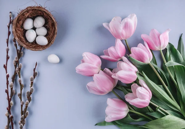 Ovos de Páscoa em ninho e flores de tulipas no fundo de primavera. Vista superior com espaço de cópia. Feliz cartão de Páscoa — Fotografia de Stock