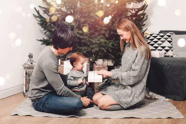 快乐的家人在客厅里送礼物，在装饰过的圣诞树后面，灯光给人一种舒适的氛围。 新年快乐圣诞佳节 — 图库照片