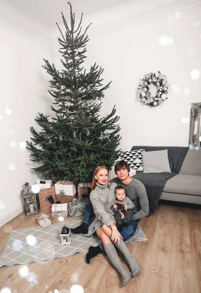 圣诞家庭，孩子在圣诞树旁笑着。 客厅里装饰着圣诞树和礼品盒,灯光给人一种舒适的氛围. 新年假期 — 图库照片