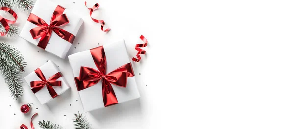 圣诞贺卡由冷杉枝条、礼品盒、红色装饰、闪光和白色背景的意粉制成。圣诞节和新年假期，bokeh，光。平躺在地上，俯瞰四周 — 图库照片
