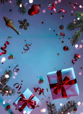 Mutlu Noeller ve yeni yıl geçmişi. Uçan süslemelerden yapılmış Noel kartı, köknar dalları, toplar, kar taneleri, ışıltılar, hediye kutuları, renkli neon mavi ve mor arka planda bokeh