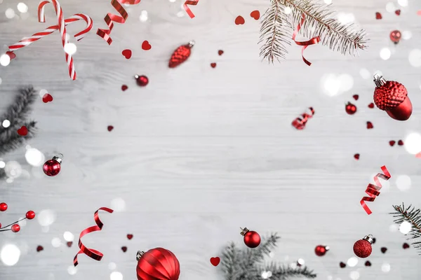 Καλά Χριστούγεννα και Πρωτοχρονιά. Χριστουγεννιάτικη κάρτα διακοπών φτιαγμένη από ιπτάμενες διακοσμήσεις, κλαδιά ελάτης, κόκκινες μπάλες, νιφάδες χιονιού, λάμψη, bokeh, φως σε ξύλινο φόντο. Επιλεκτική εστίαση — Φωτογραφία Αρχείου