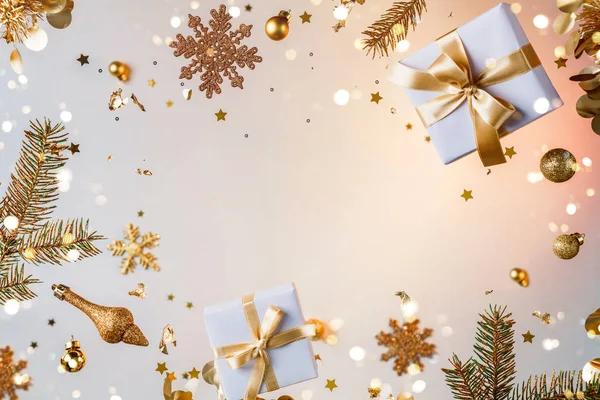 Merry Christmas and New Year background. Xmas holiday card made of flying decorations, gold fir branches, balls, snowflakes, sparkles, gift boxes, bokeh, light on golden background. Selective focus