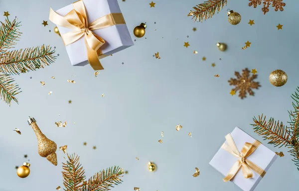 Merry Christmas and New Year background. Xmas holiday card made of flying decorations, gold fir branches, balls, snowflakes, sparkles, gift boxes, bokeh on light blue background. Selective focus