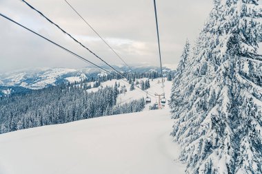 Kayak asansörü ya da karlı orman manzarasında füniküler. Karla kaplı köknar ağaçları olan donmuş dağların panoramik manzarası. Kış tatili ve kayak merkezinde dinlenme
