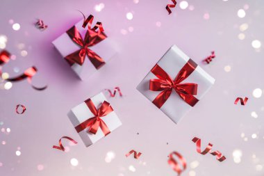Merry Christmas and New Year background. Xmas holiday card made of flying decorations, red balls, snowflakes, sparkles, gift boxes, bokeh, light on pink background. Selective focus