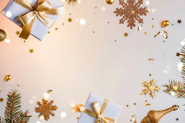 Merry Christmas and New Year background. Xmas holiday card made of flying decorations, gold fir branches, balls, snowflakes, sparkles, gift boxes, bokeh, light on golden background. Selective focus