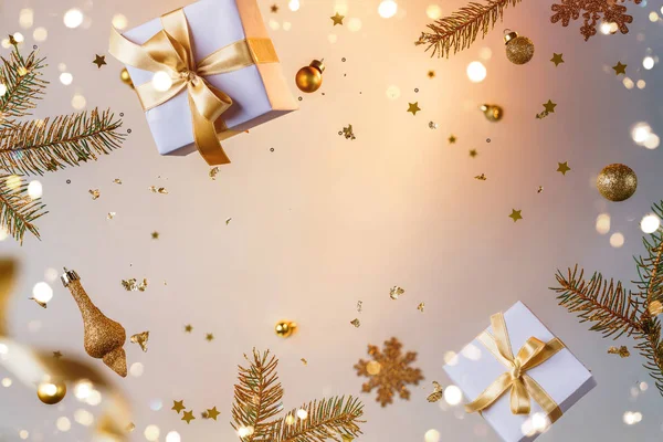 Frohe Weihnachten und Neujahr Hintergrund. Weihnachtskarte aus fliegenden Dekorationen, Tannenzweigen, Kugeln, Schneeflocken, Funkeln, Geschenkschachteln, Bokeh, Licht auf goldenem Hintergrund. Selektiver Fokus — Stockfoto