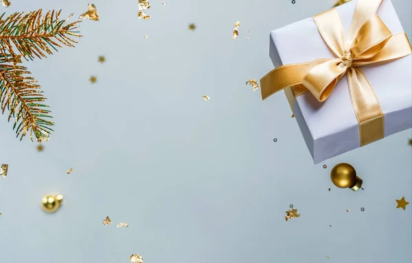 Веселого Різдва та Нового року. Різдвяна святкова листівка з літаючих прикрас, золотих ялинових гілок, кульок, сніжинок, блискіток, подарункових коробок, боке на світло-блакитному тлі. Вибірковий фокус — стокове фото