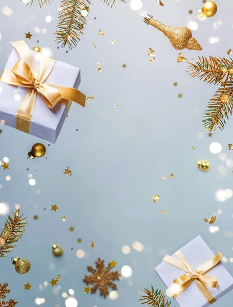 Merry Christmas and New Year background. Xmas holiday card made of flying decorations, gold fir branches, balls, snowflakes, sparkles, gift boxes, bokeh on light blue background. Selective focus