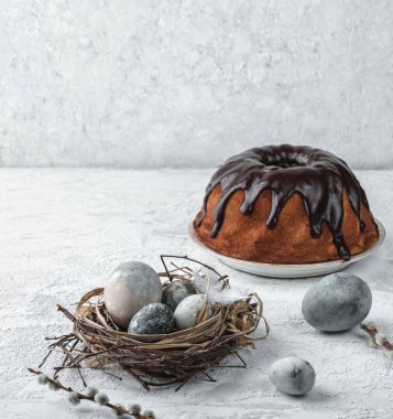 Beyaz arka planda paskalya yumurtaları, çikolatalı pasta ve bahar çiçekleri. Mutlu Paskalyalar, seçici odaklanma