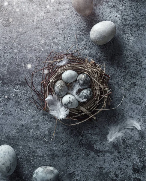 Húsvéti tojás madárfészekben, kék hátterű tollakkal, fénnyel, bokeh. Kellemes húsvéti ünnepeket, felülnézetet, lapos fekvést — Stock Fotó