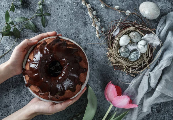 Kezek kezében húsvéti torta csokoládéval könnyű háttérrel húsvéti tojás fészekben és tavaszi tulipán virágok. Kellemes húsvéti ünnepeket, felülnézetet, lapos fekvést — Stock Fotó