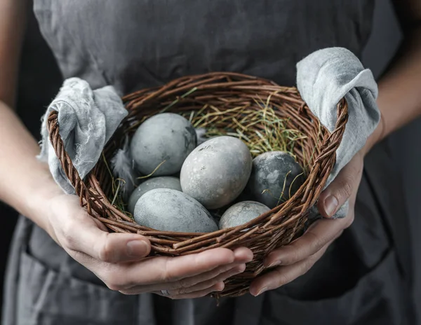 Nő kezét fonott kosár húsvéti tojás sötét háttérrel. Kellemes húsvéti ünnepeket, szelektív fókuszt — Stock Fotó