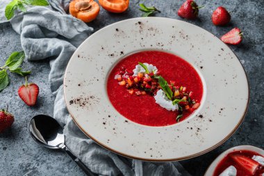 Şeftalili çilekli gazpacho çorbası, kremalı ve açık mavi arka planda naneli. Yaz meyveli tatlı, sağlıklı vejetaryen yemeği, üst manzara.