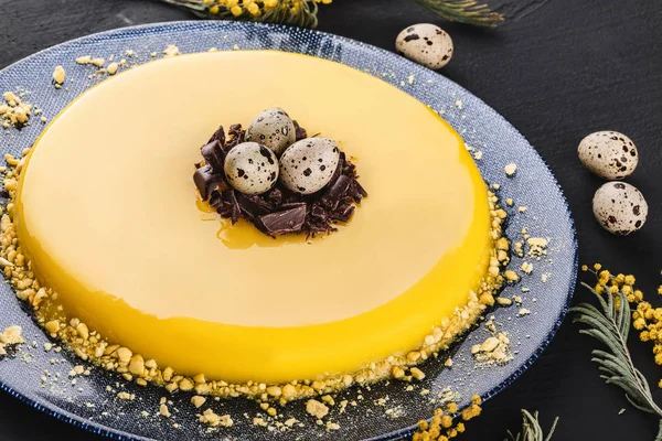 黄色の鏡釉とイースターケーキ,チョコレート,春の花,暗い石の背景にウズラの卵.ハッピーイースターお祝い。トップ表示 — ストック写真