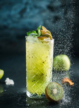 Elma ile taze kivi kokteyl, nane ve pudra şekeri kavanoz cam koyu mavi arka plan üzerinde. Stüdyoda dondurucu hareketle içki, pudra şekeri, damla. Yaz soğuk içecek ve kokteyl
